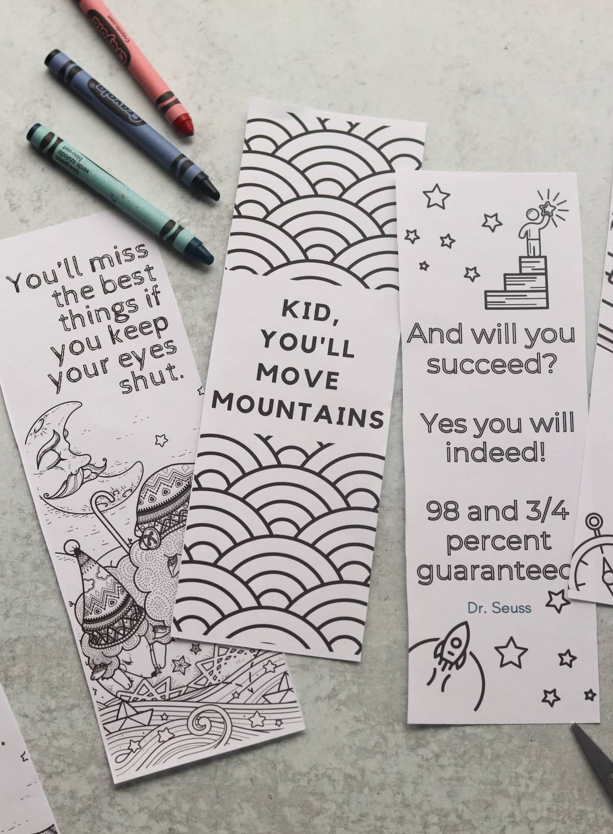 Close up of three of the printed coloring bookmarks with crayons. 