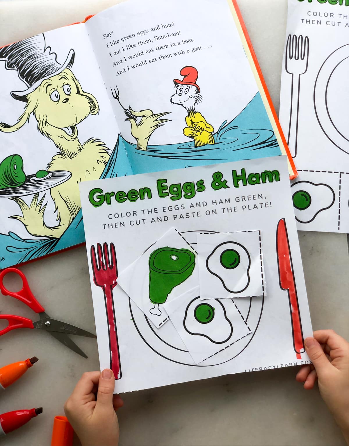 Two child's hands holding the finished worksheet near an open copy of Green Eggs and Ham. 