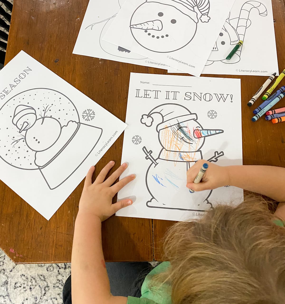 A child coloring a snowman coloring sheet.