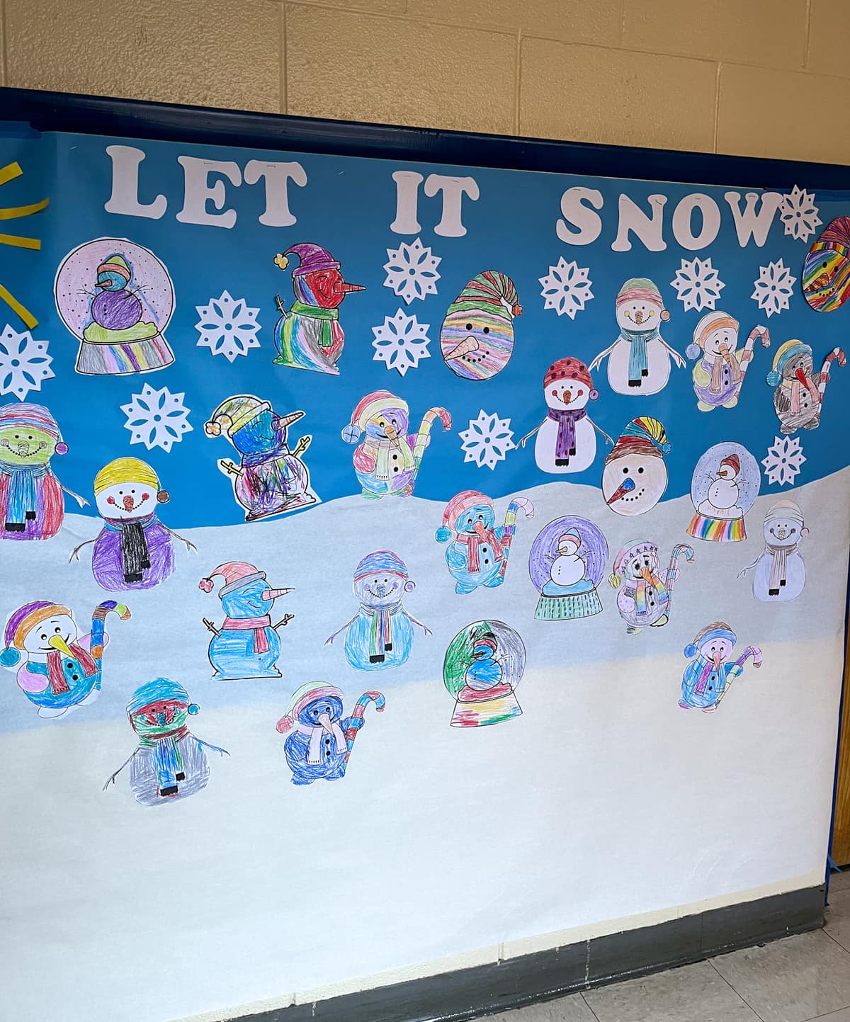 Hallway decoration with colorfully cut out snowman coloring on a blue, snowy background. 