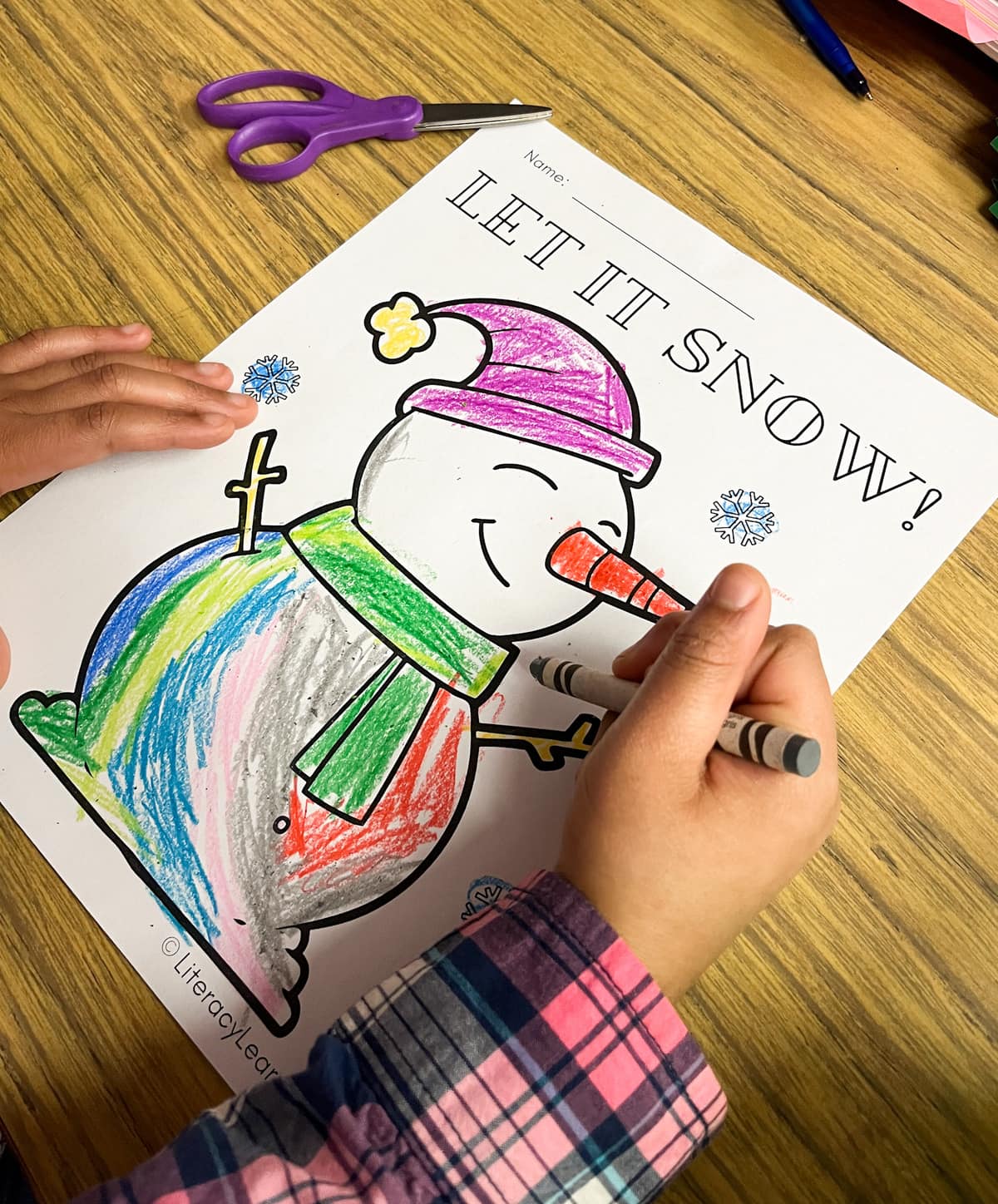 Close up of a hand coloring one of the snowman coloring pages.