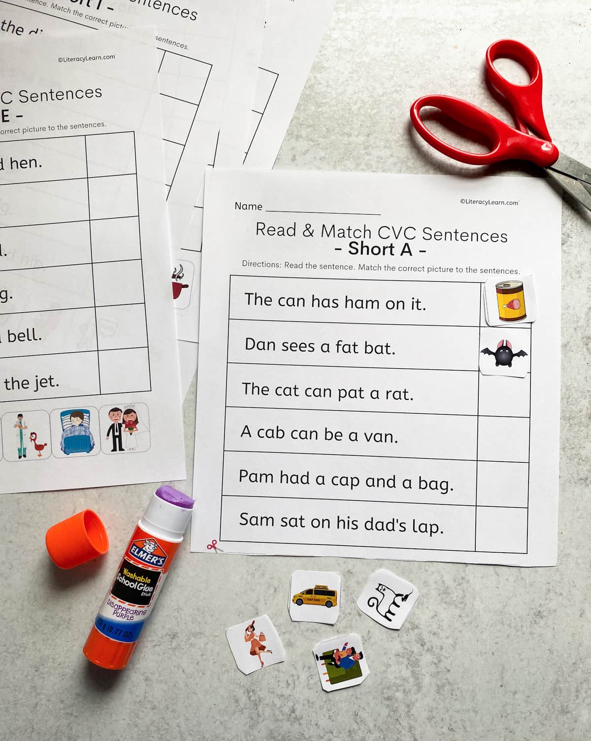 The printed CVC sentence worksheets surrounded by scissors and a glue stick. 