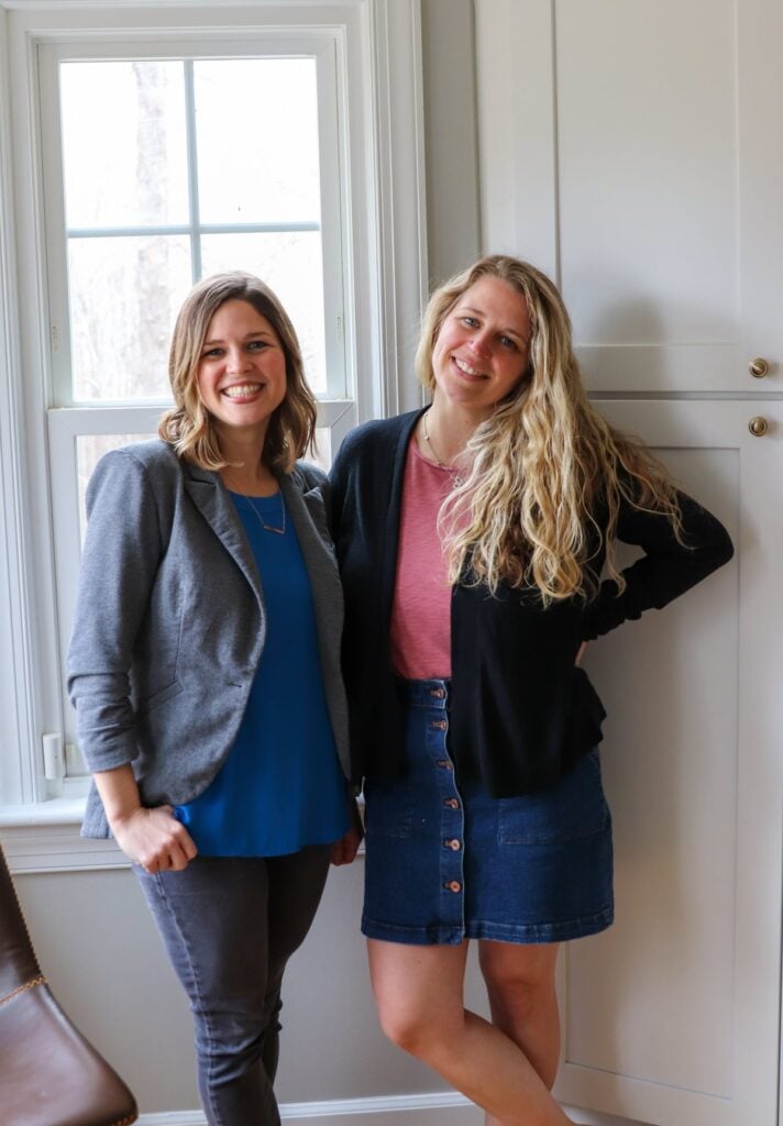 Two smiling women standing side by side.