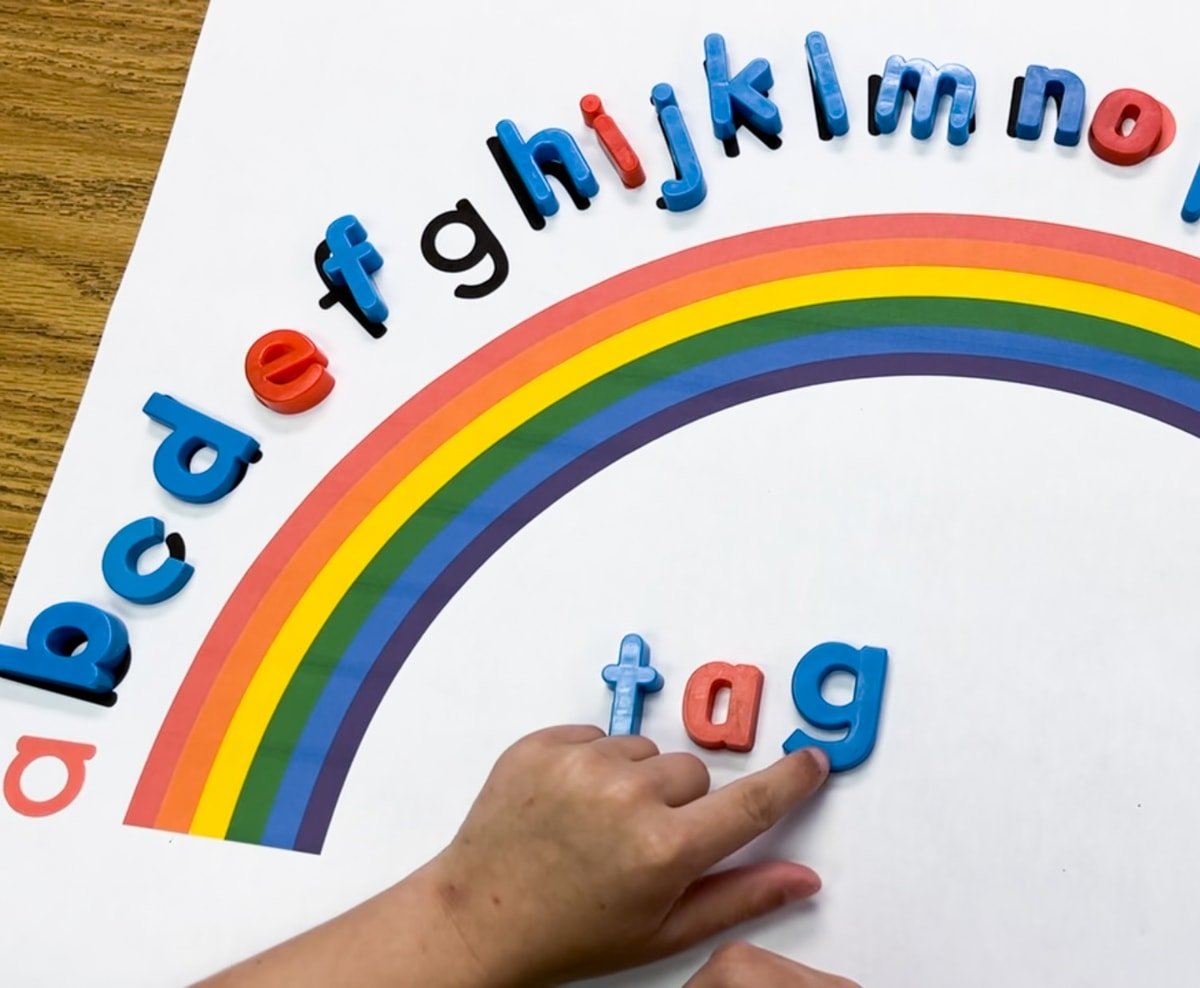 A child building the word "tag" using magnetic letters on the alphabet arc.