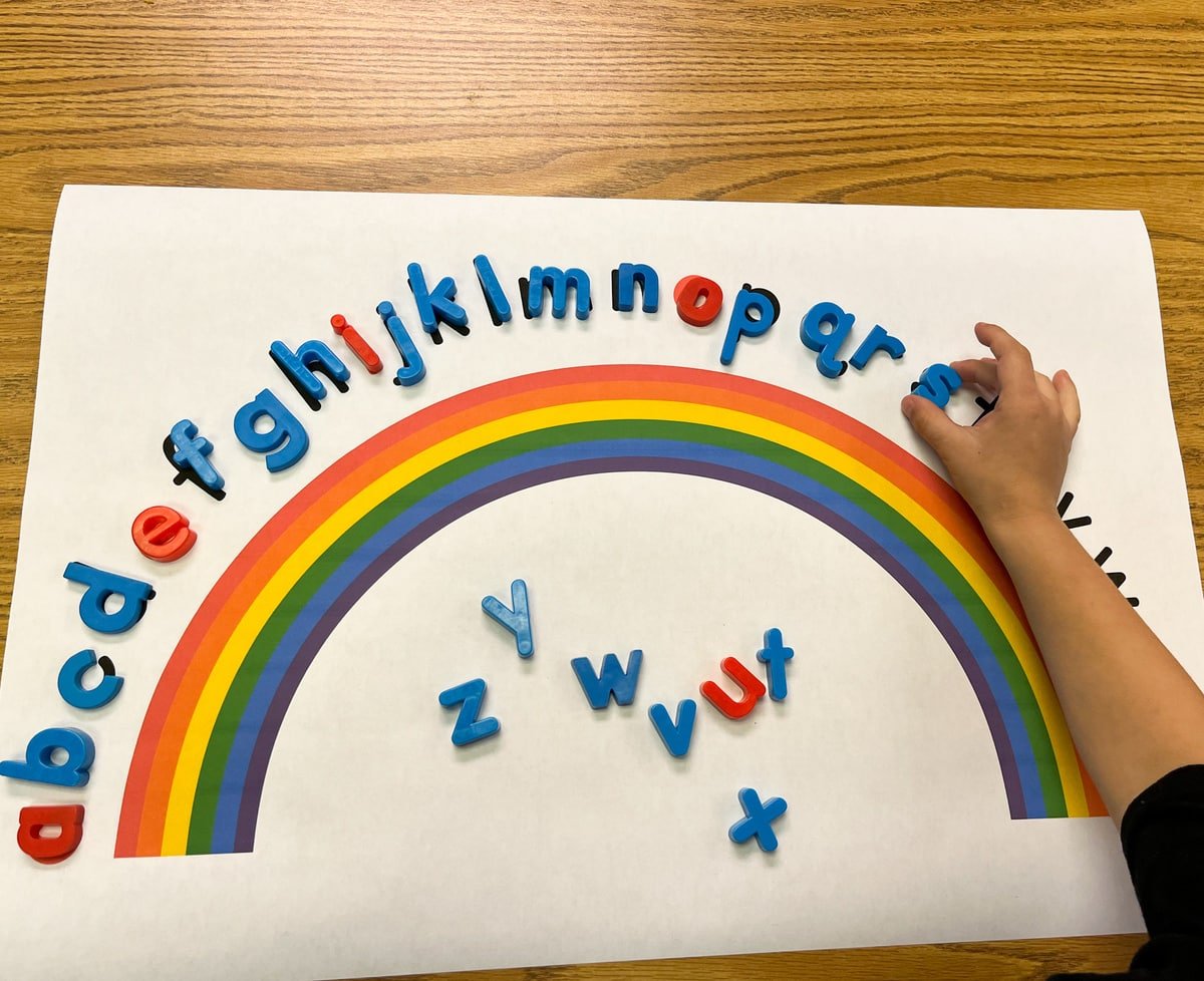 A child placing matching letters on the colorful rainboow alphabet arc.