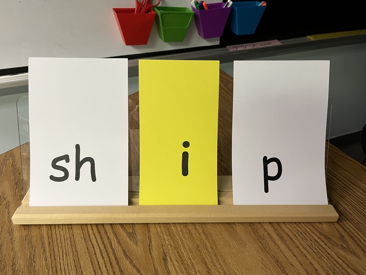 Photograph of a blending board with phonograph cards sh, i, p to spell the word ship.