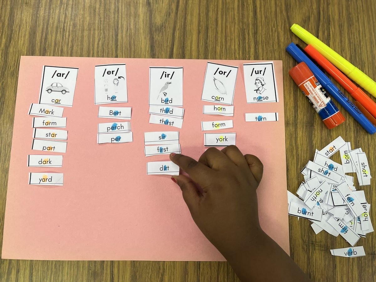 Photograph of student with the worksheet cut apart sorting words by r-controlled vowels.