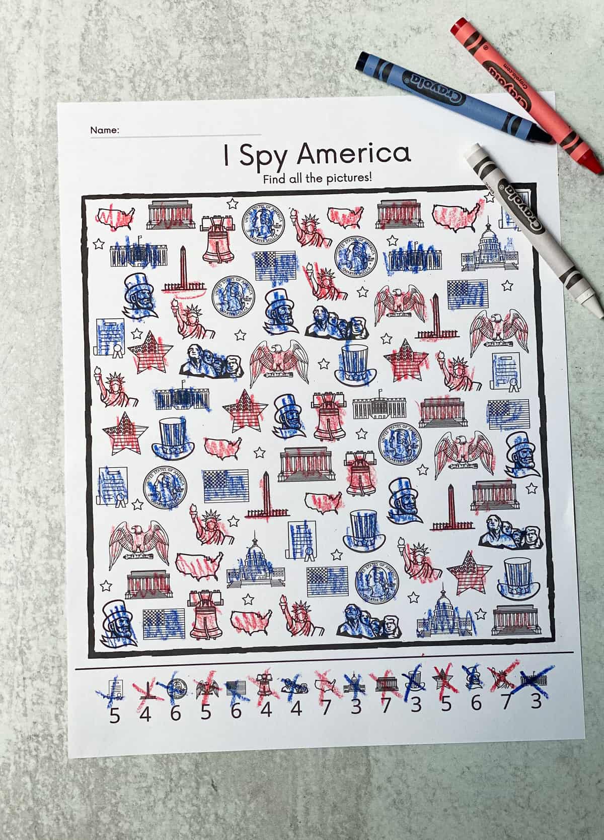 The printed and completed I Spy America worksheet with a red, white and blue crayon.