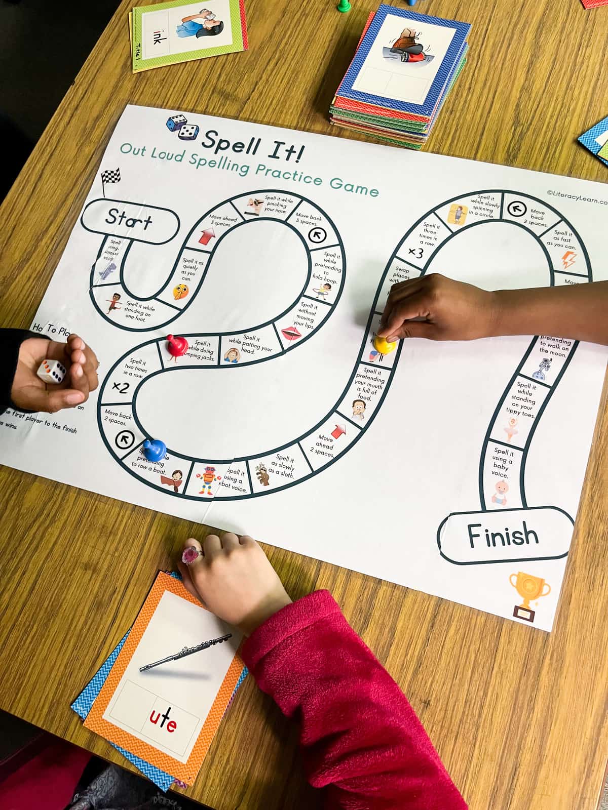 Children playing the spelling board game, printed on large paper. 