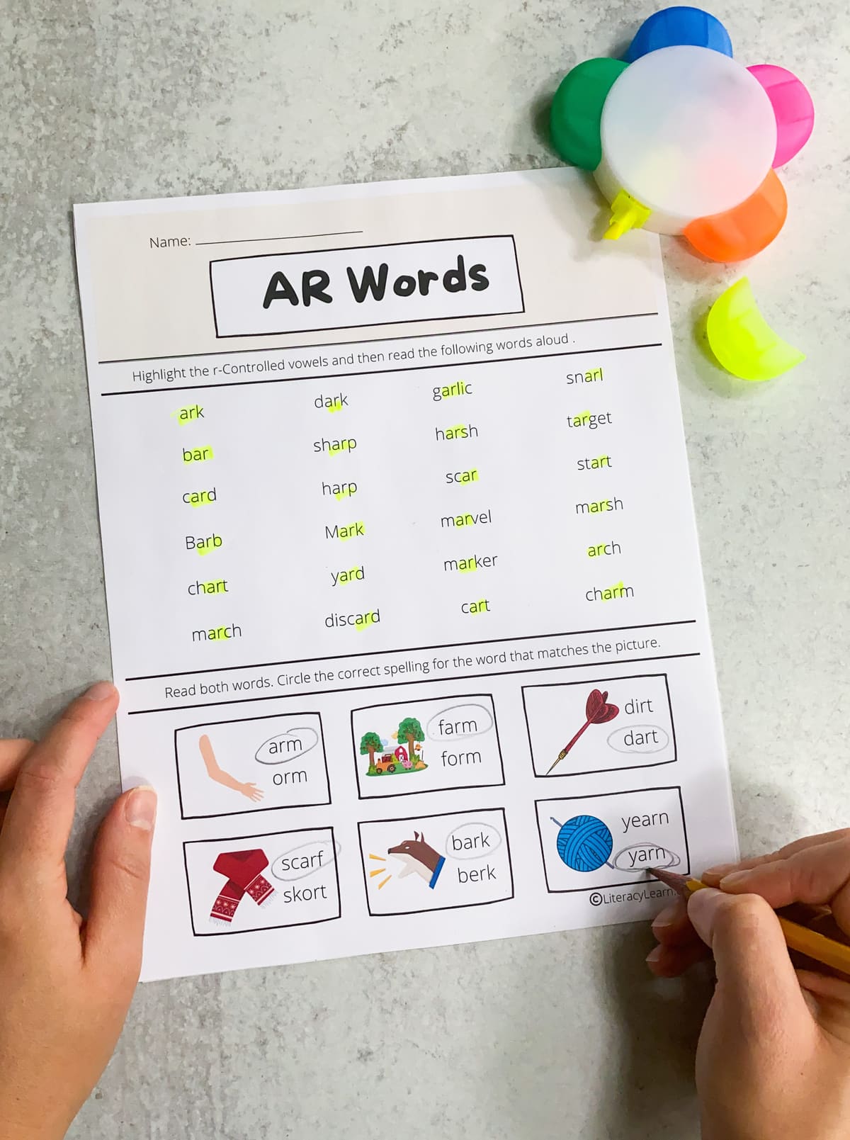 Hands holding a pencil completing the printed AR words worksheet.