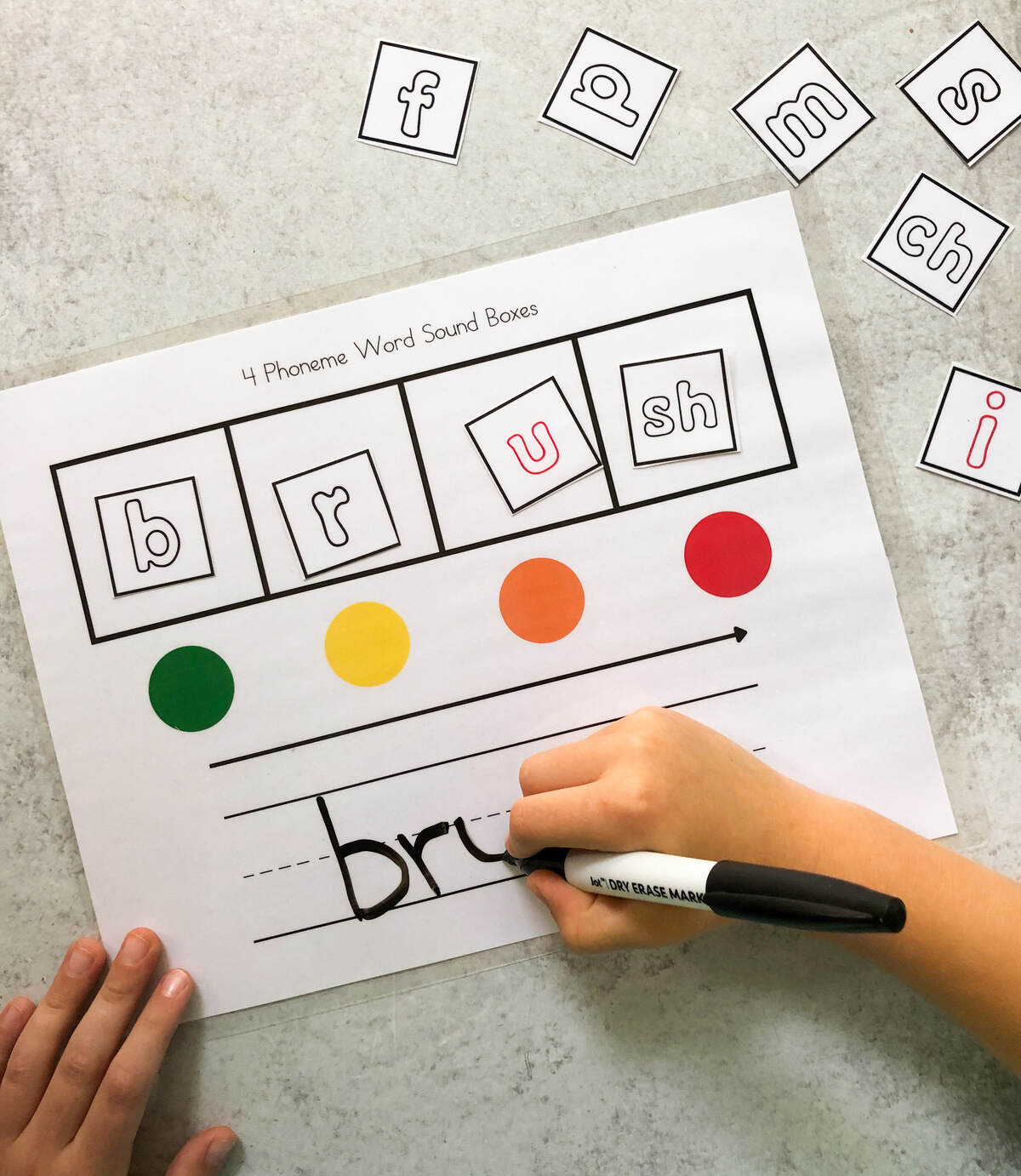 A child using a sound box worksheet to map the word "brush."