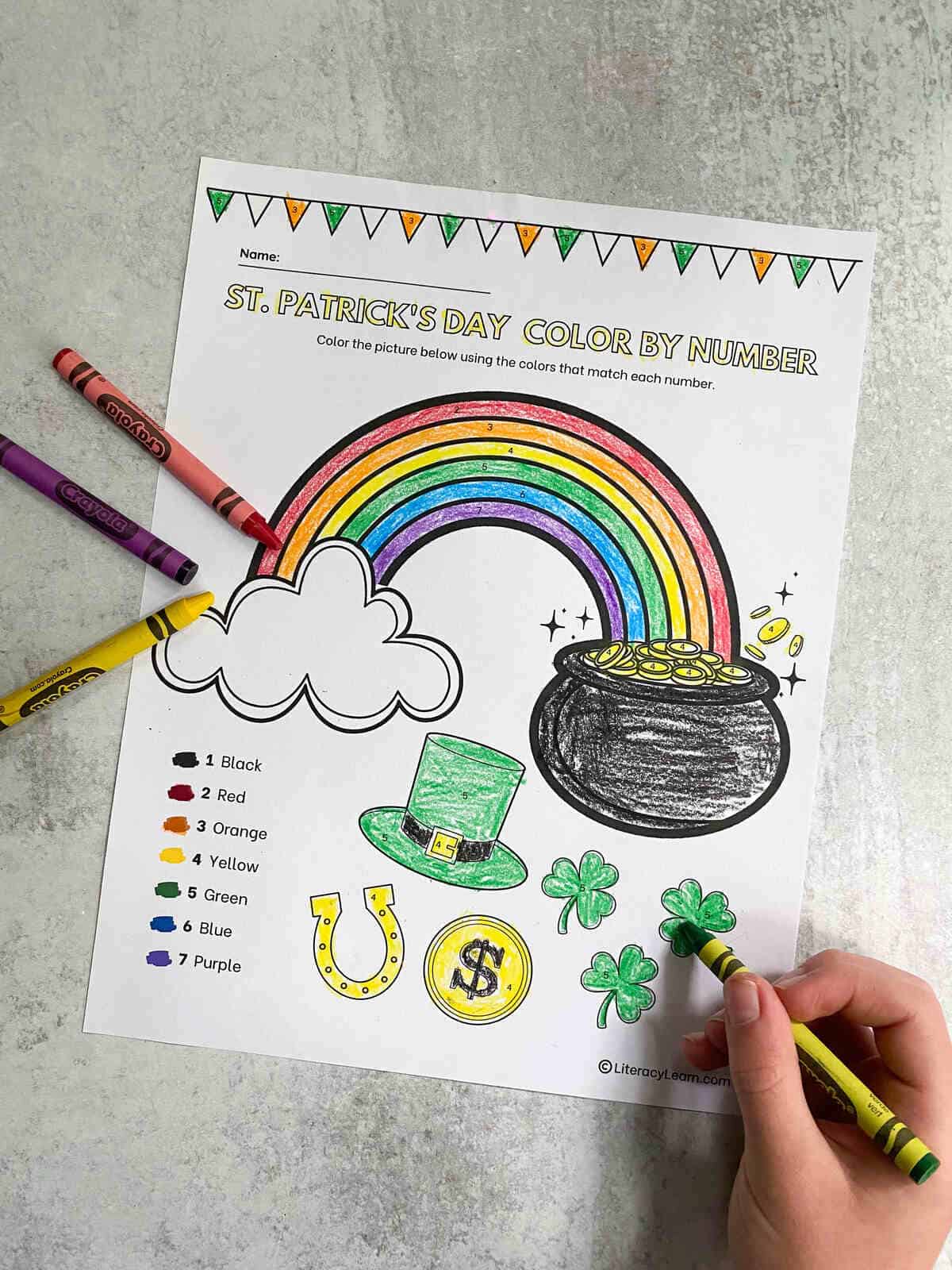 A child's hand coloring a the printable worksheet. 