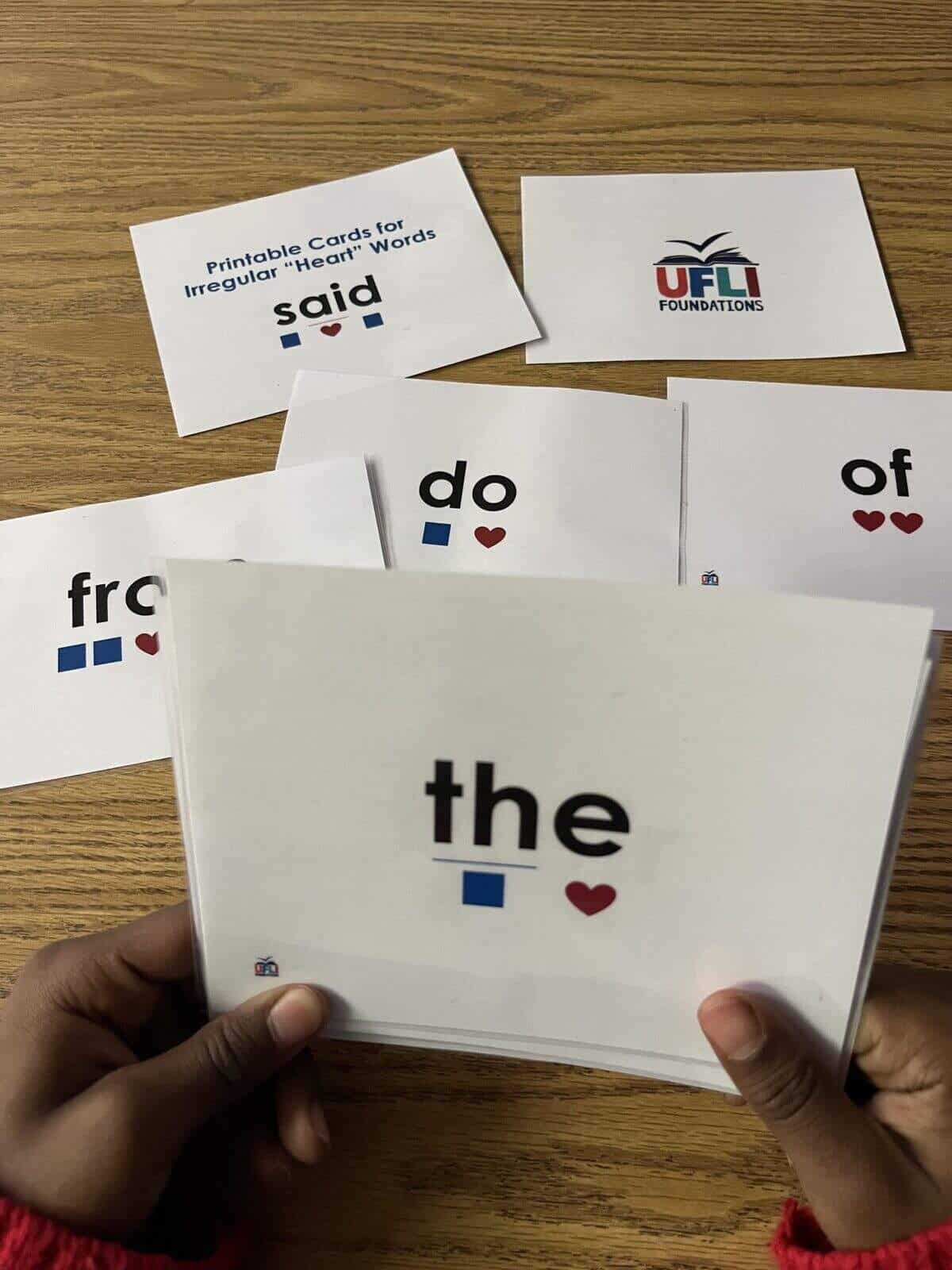 A photo of a student's hands holding the Heart Words Word cards from UFLI.