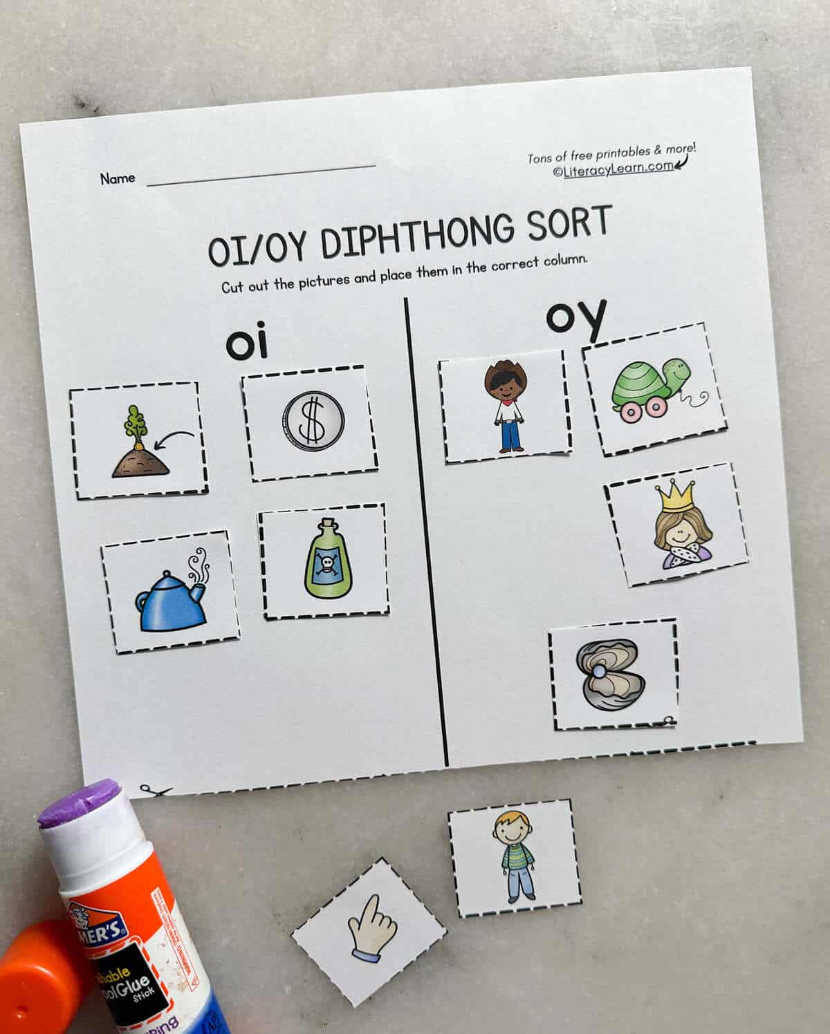 The printed and completed oi/oy picture sort worksheet with a glue stick.
