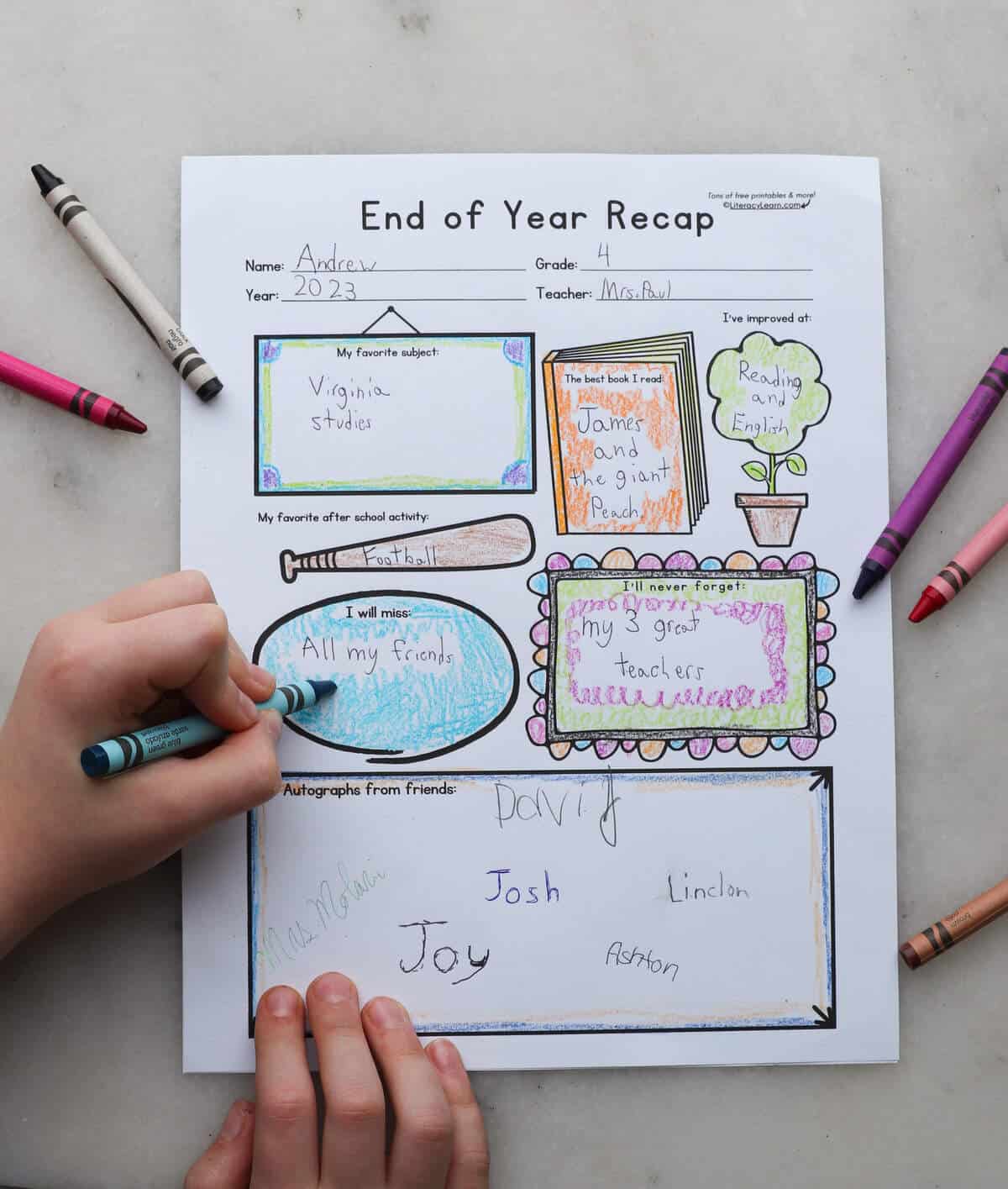A student's hands coloring in and writing answers on the printed Last Day of School worksheet. 