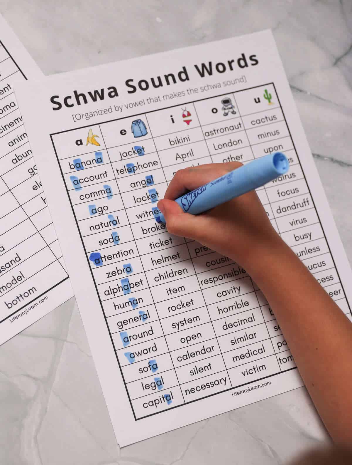 A student highlighting the schwa in each word on a printed word list. 