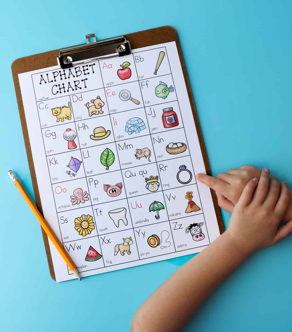 Blue background and clipboard with free ABC chart on it with a child's hand pointing to the letters.