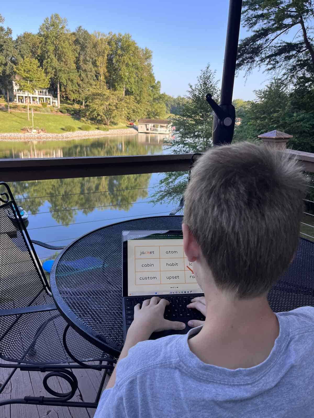 Photograph of a boy doing his lexercise basic therapy on the computer at the lake.