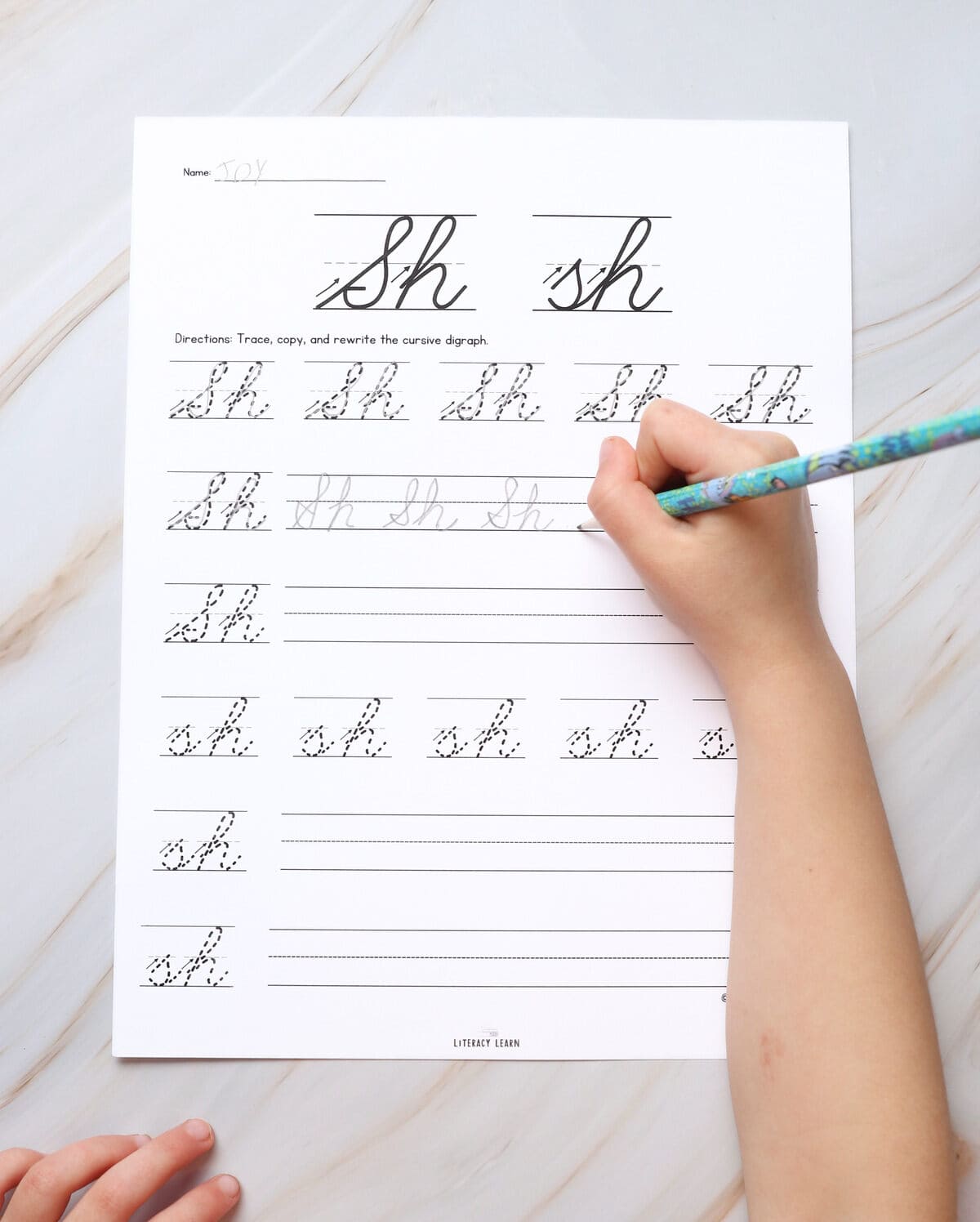 A printed digraph sh cursive writing worksheet with a child tracing then writing the letters.