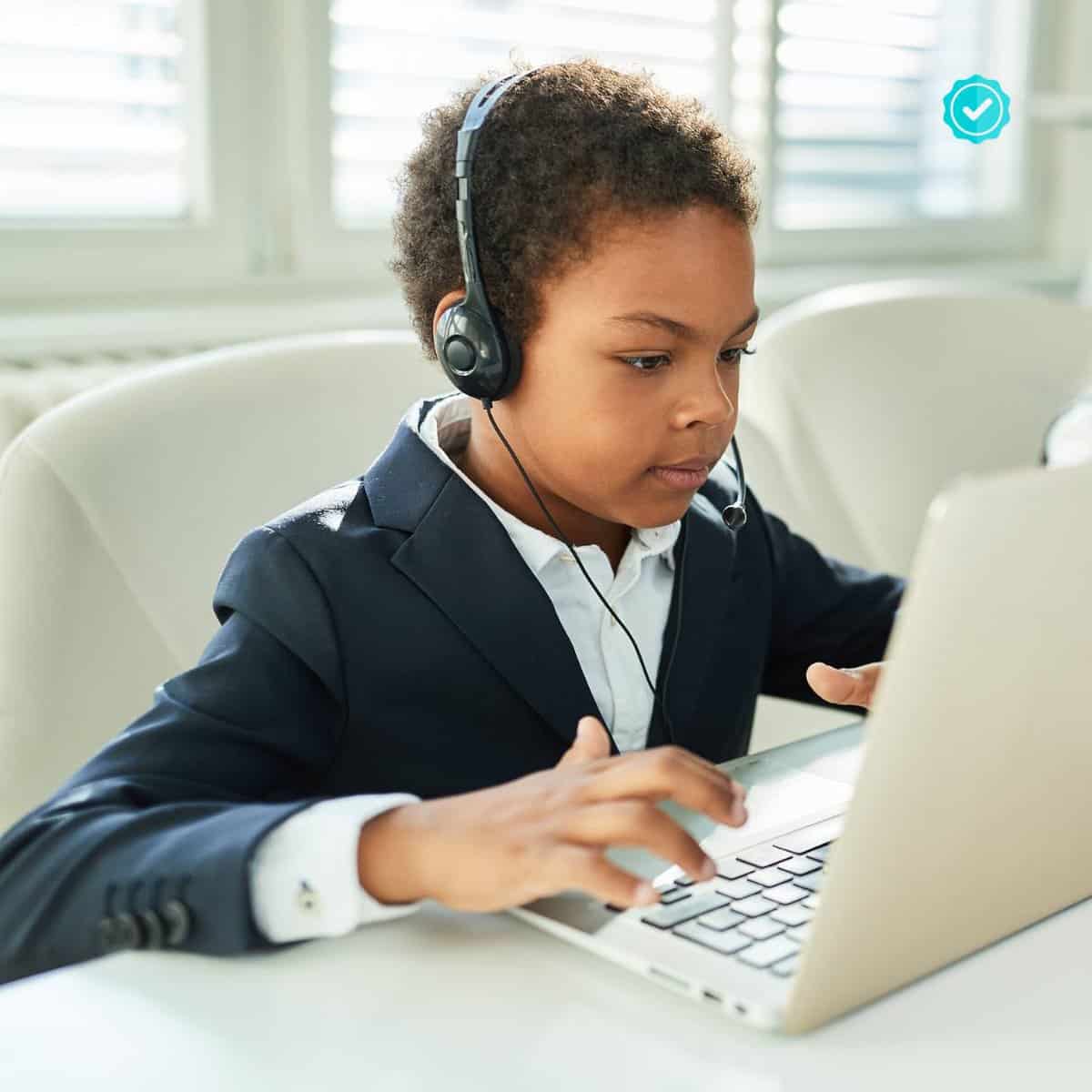 A child with headphones working at a laptop.