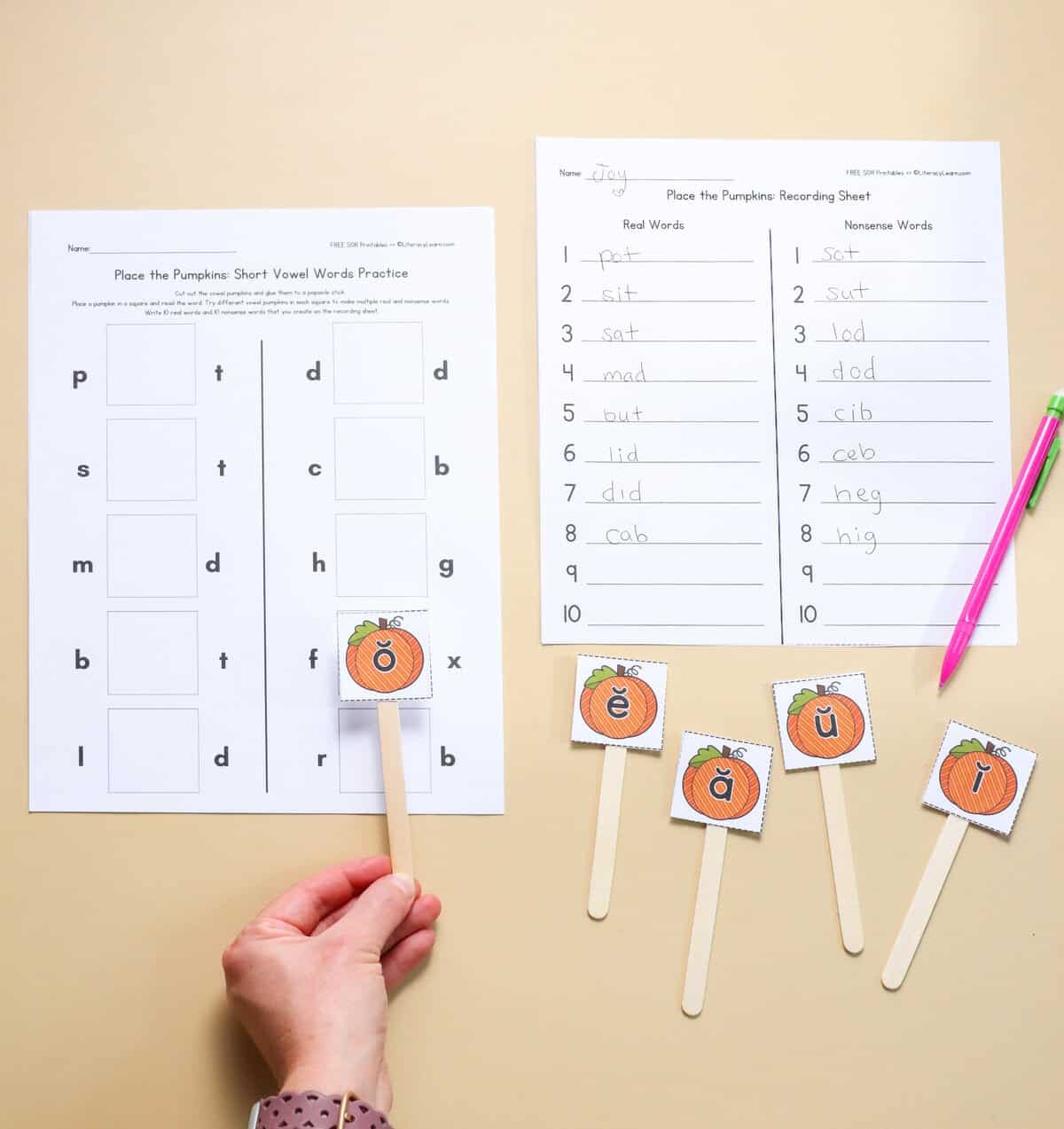 A hand holding the letter o to build words next to a recording sheet.