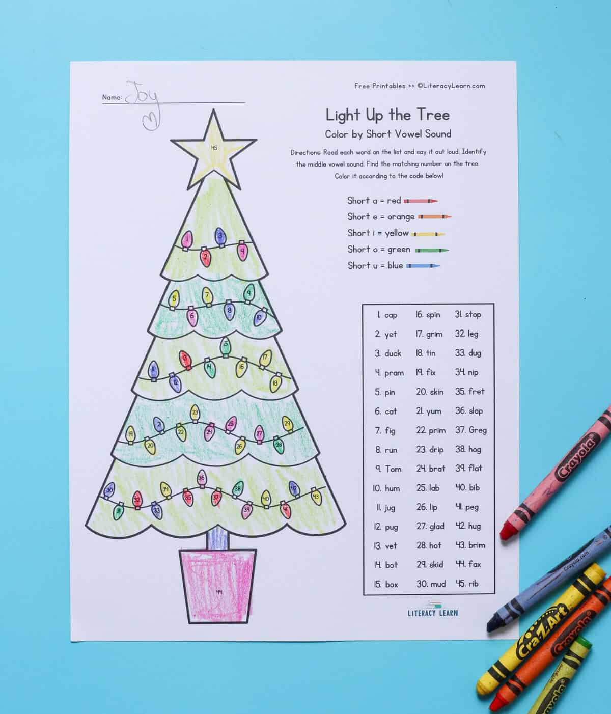 A printed Christmas tree color-by-code worksheet with CVC words. 