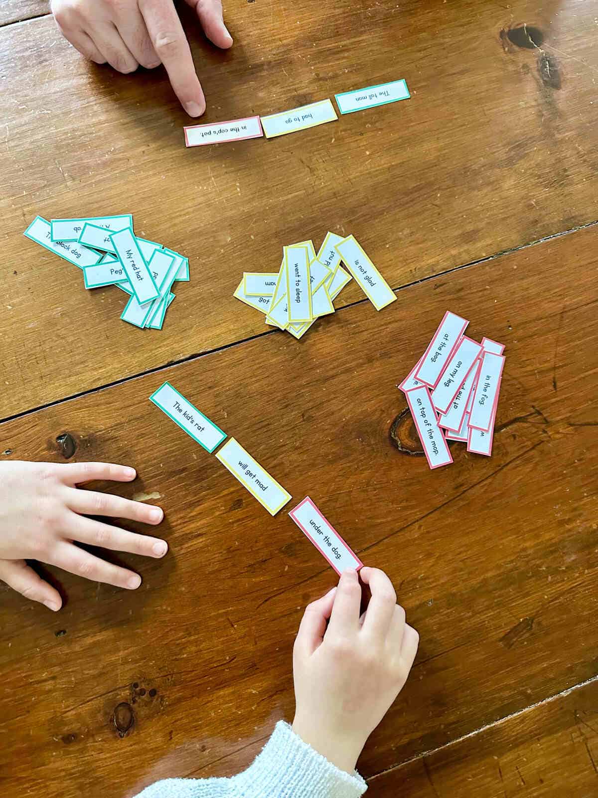 A child's hands using phrase strips to create a sentence.