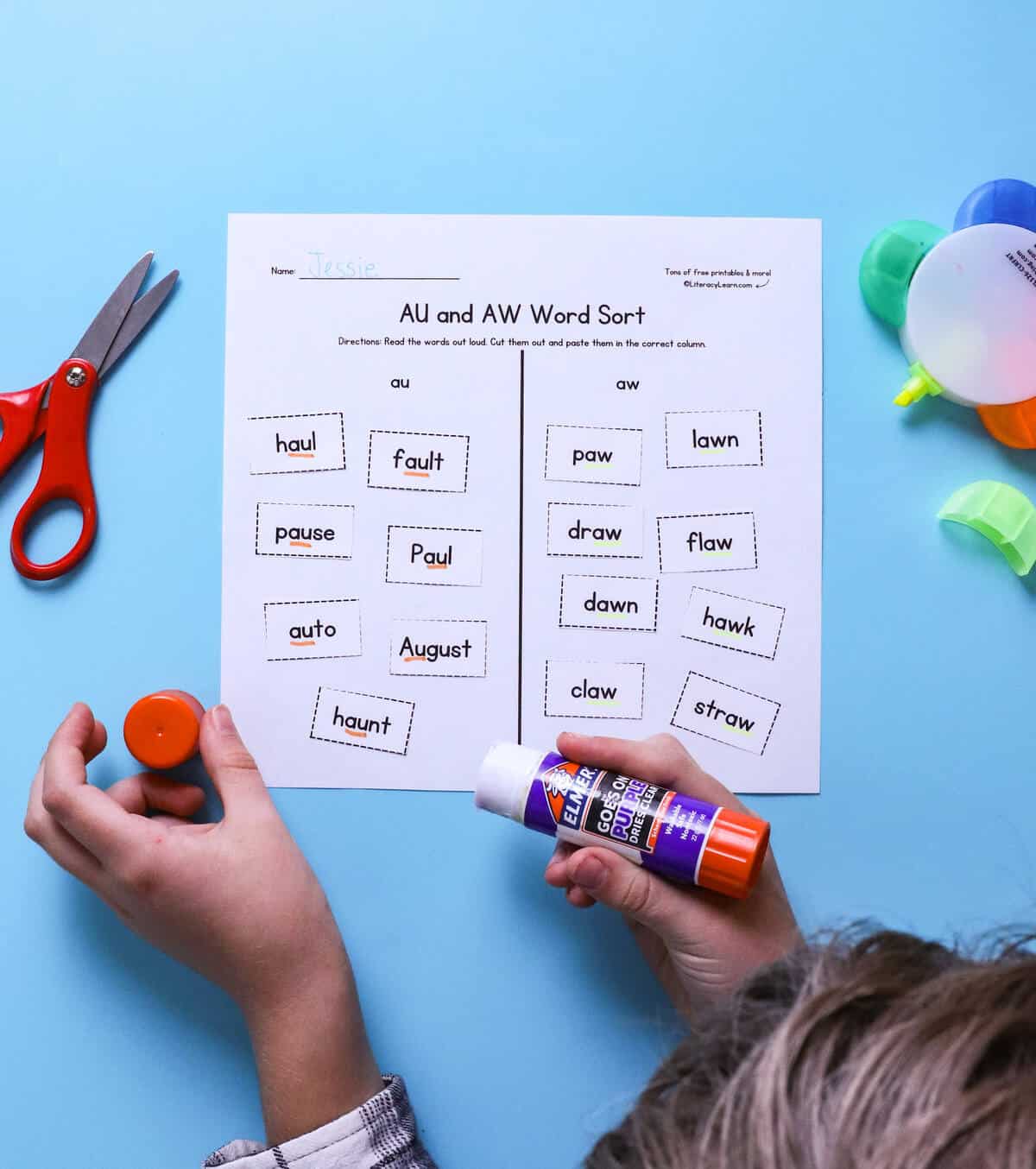 A child completing a printed Au/Aw word sorting worksheet.