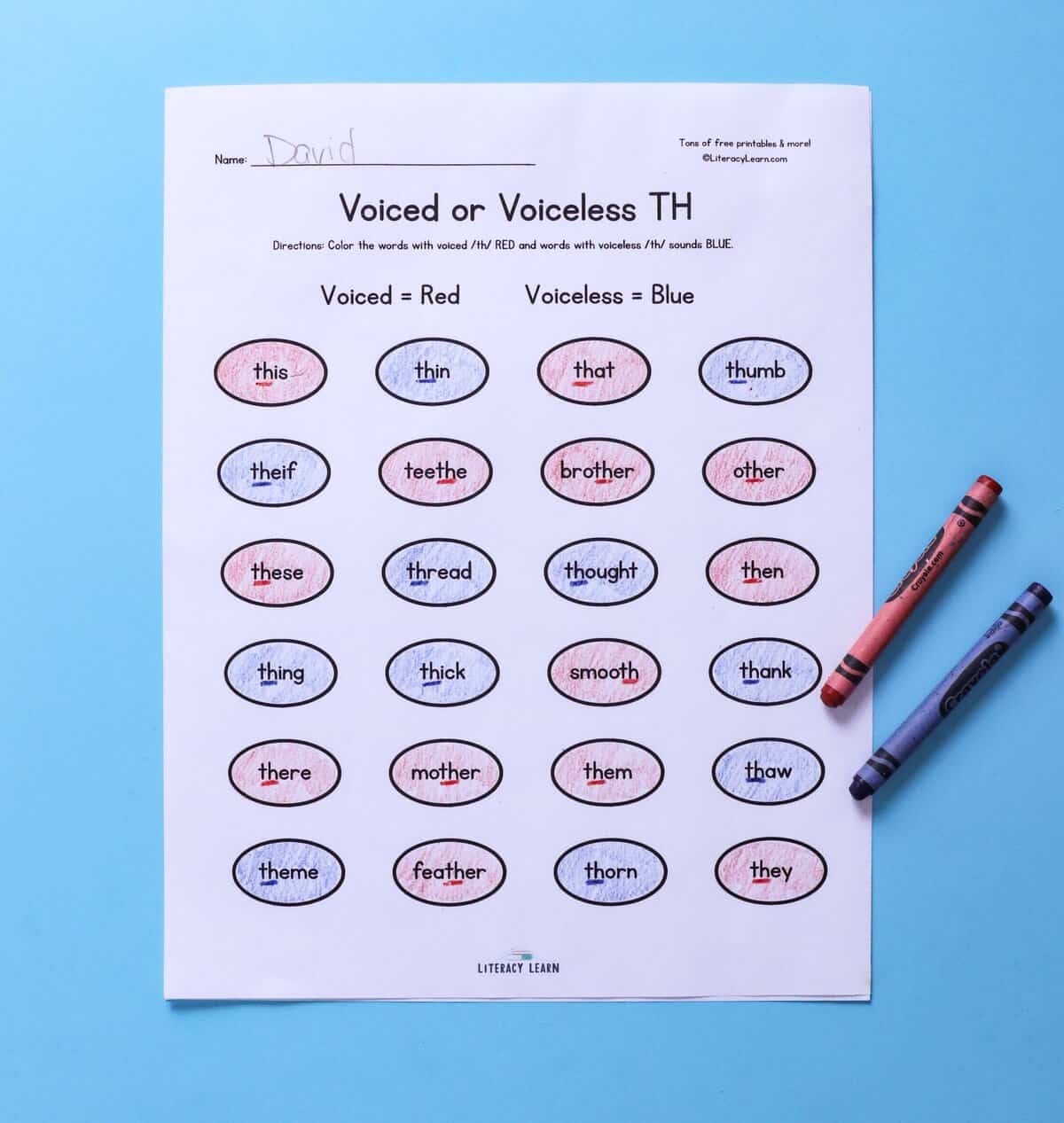 Photo of worksheet with words with th colored red and blue representing voiced and voiceless th sounds.