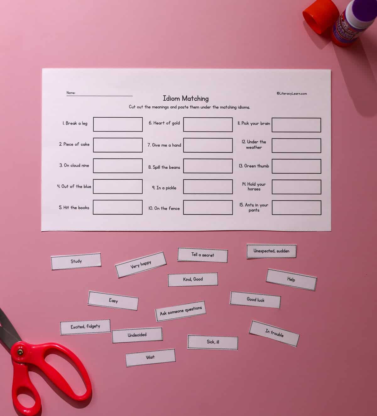 A cut and paste idioms matching worksheet with scissors and a glue stick.